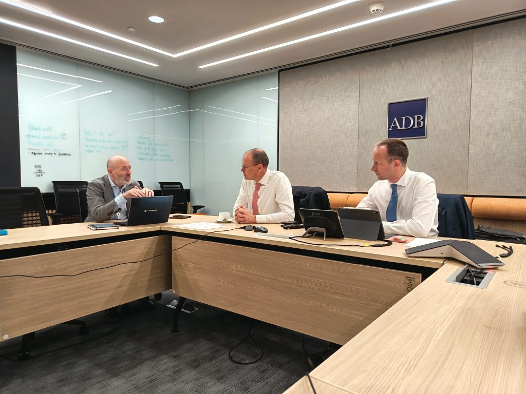 Three men sitting behind the table and takling